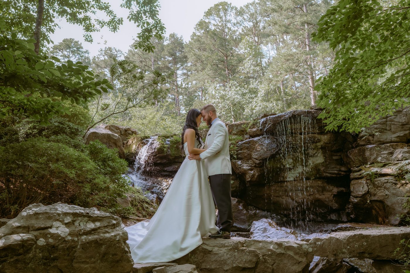 Wedding couple kissing by a waterfall at Anthony Chapel in Central Arkansas
