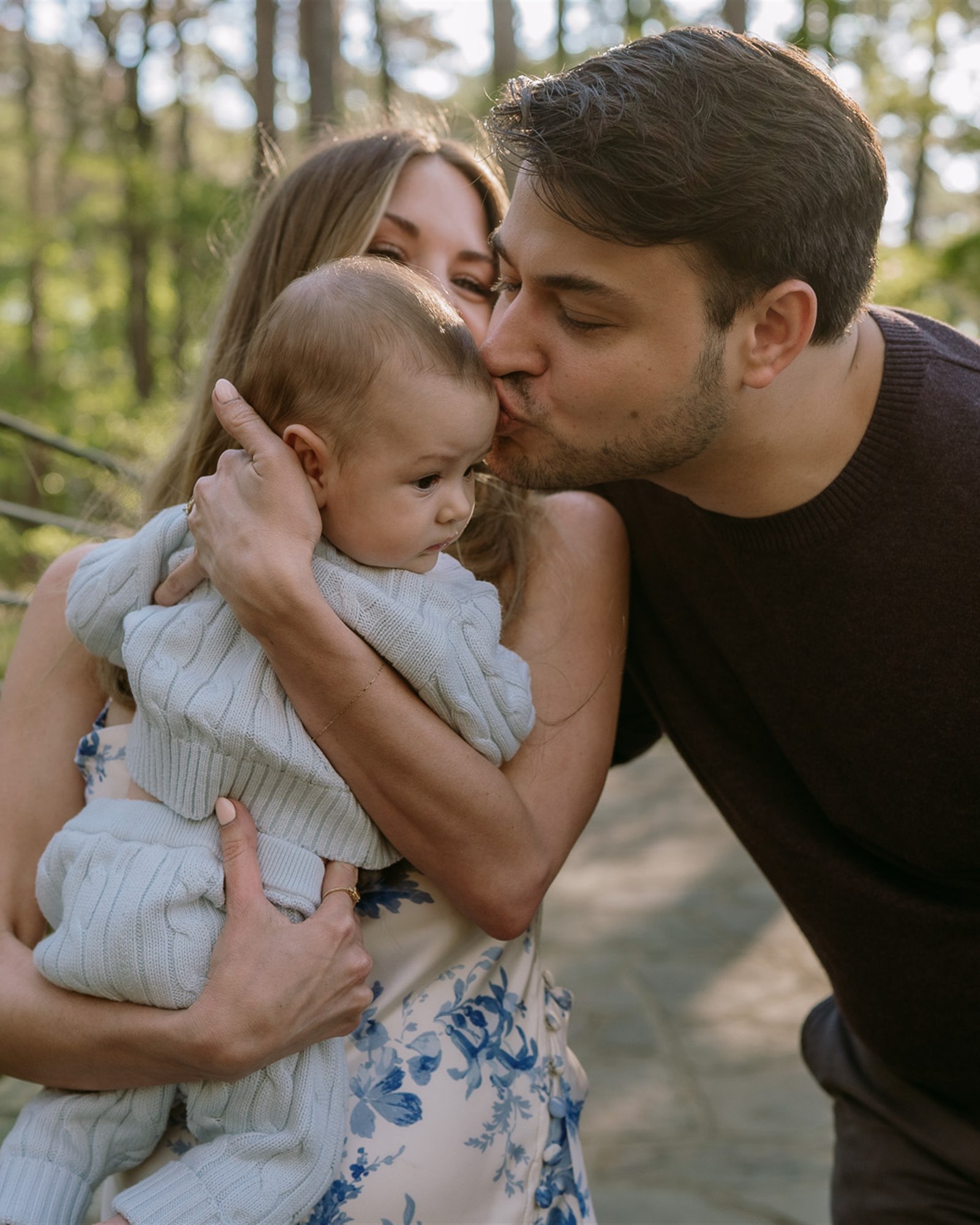 Family of three sharing a kiss during a Garvan Woodland Gardens family session in Arkansas