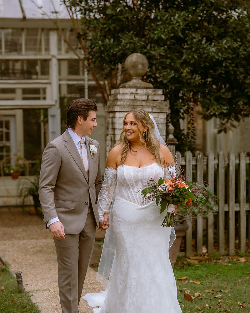Bride and groom walking past the conservatory at an Arkansas wedding venue