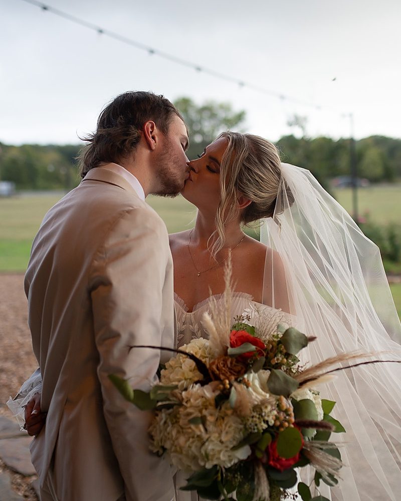 Bride and groom kissing under string lights at an Arkansas wedding